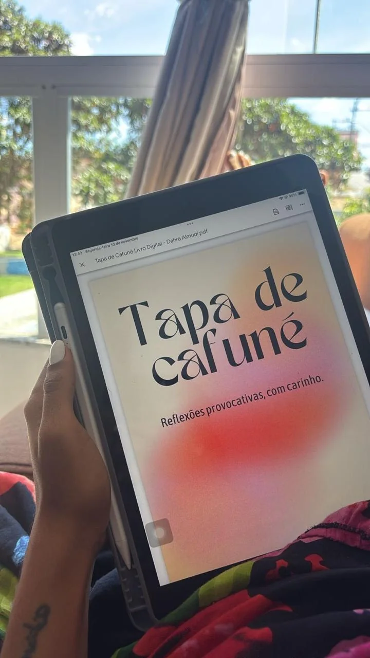 Tablet exibindo a capa do livro Tapa de Cafuné, lido em uma rede ao ar livre